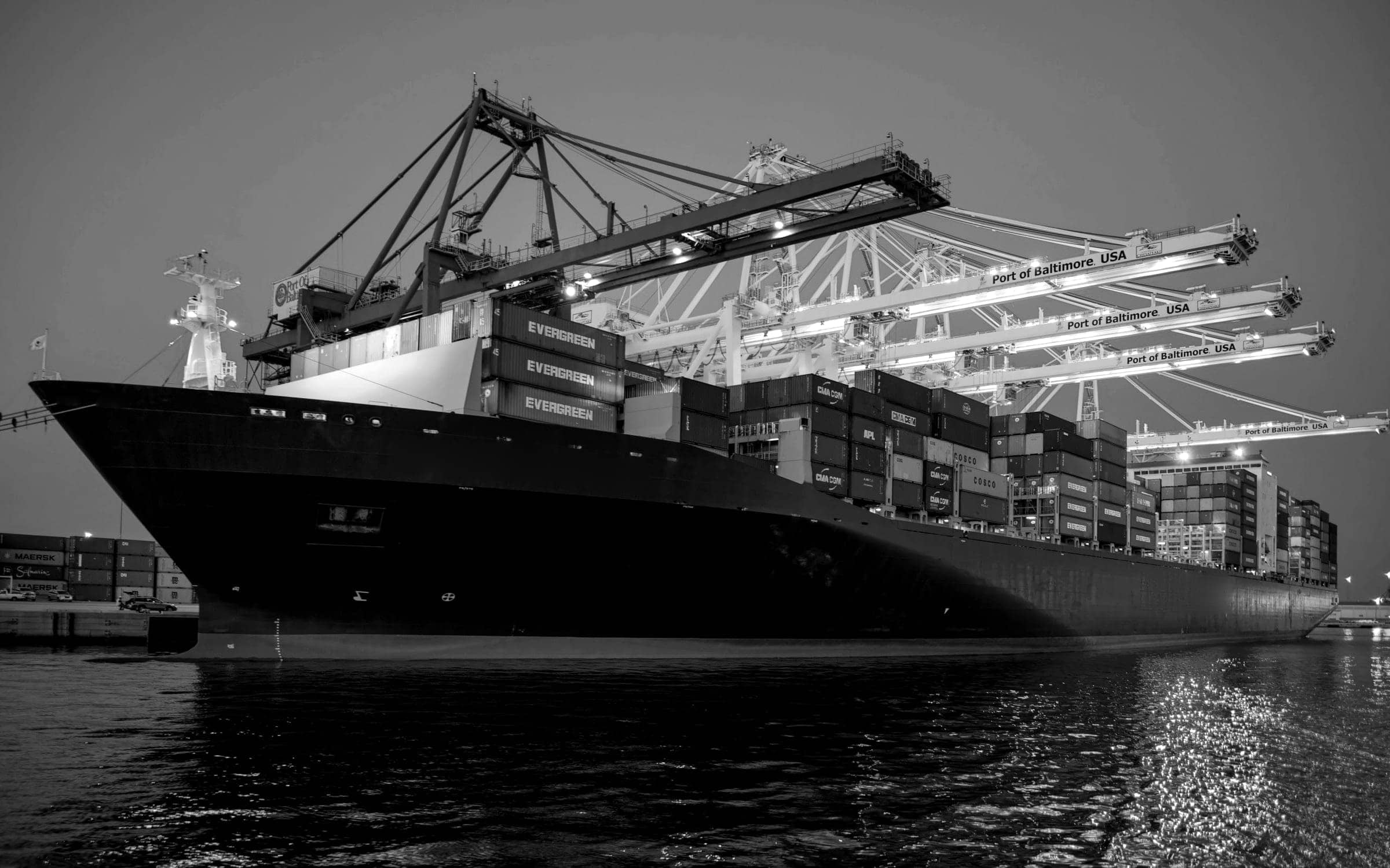 Container ship at berth under gantry cranes at dusk